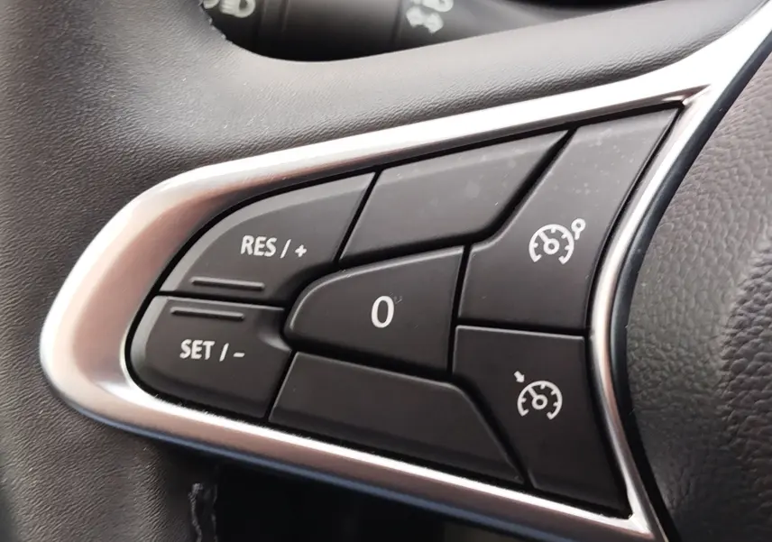 Gros plan sur les commandes de régulateur de vitesse au volant de la Renault Clio V Business gris platine, intérieur noir.