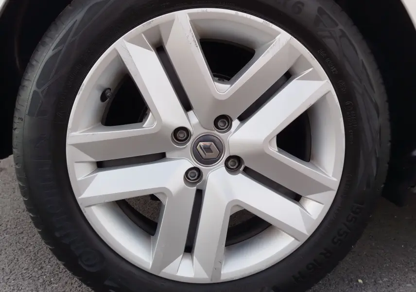 Gros plan sur la jante alliage argentée avec logo Renault au centre, montée sur pneu Continental d'une Clio V gris platine.