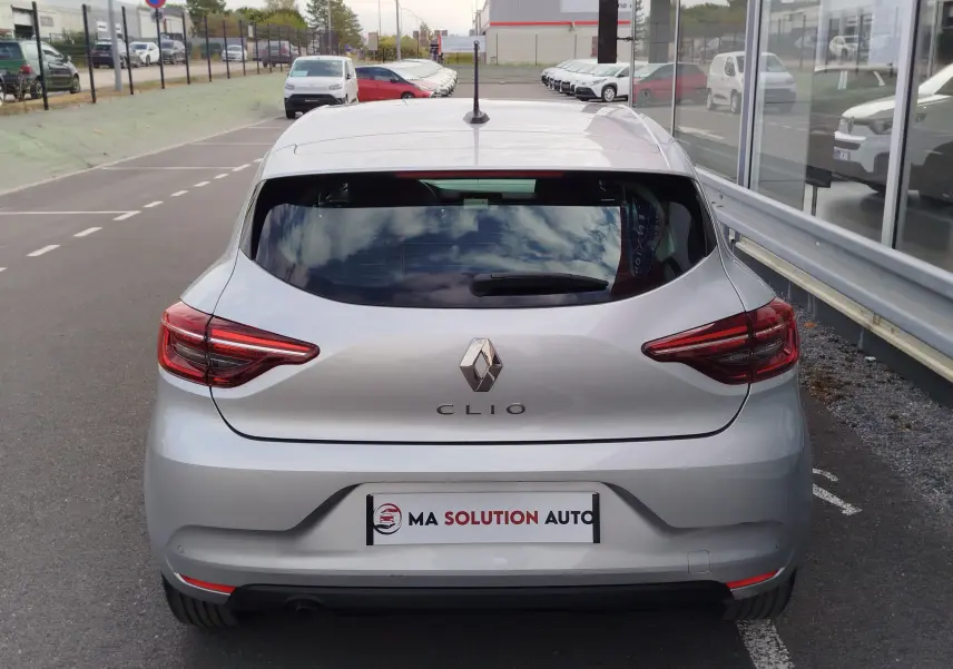 Vue arrière d'une Renault Clio V gris platine garée, avec feux arrière LED et logo Renault bien visibles.