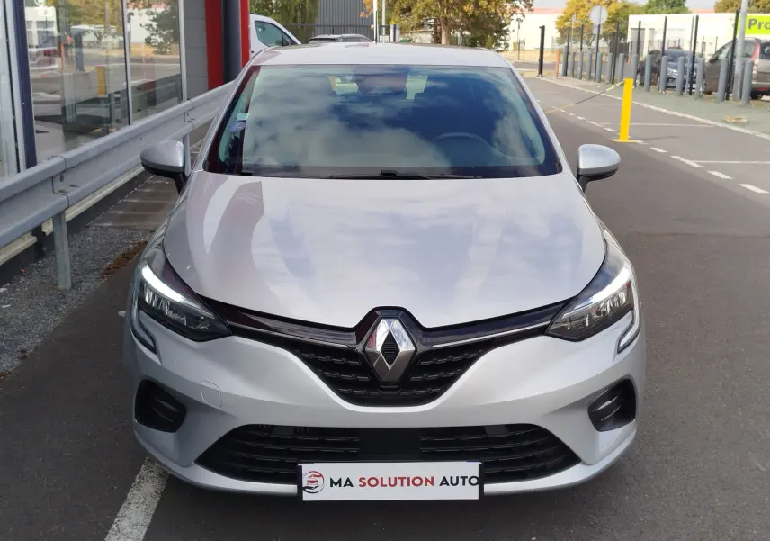 Vue frontale d'une Renault Clio V Business gris platine avec phares LED allumés sur un parking extérieur.