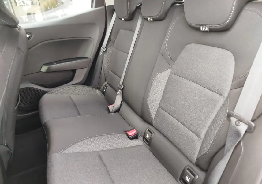 Vue latérale intérieure sur les sièges arrière gris foncé avec surpiqûres et ceintures de sécurité visibles d'une Renault Clio V.