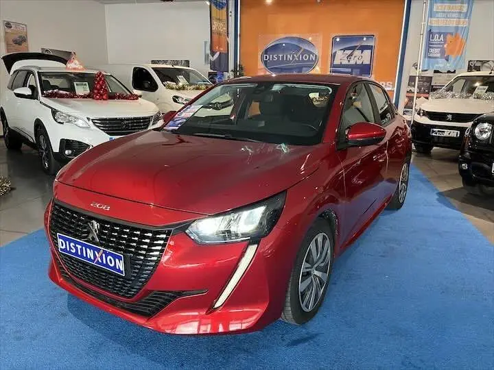 Peugeot 208 rouge Elixir Metal vue 3/4 avant droit dans un showroom avec éclairage intérieur.