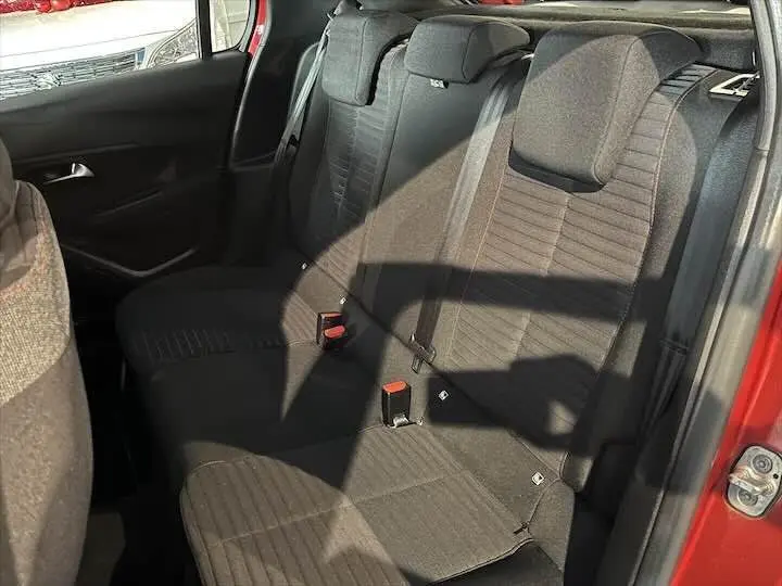 Vue intérieure sur les sièges arrière noirs d'une Peugeot 208 rouge Elixir Metal, avec ceinture de sécurité visible.