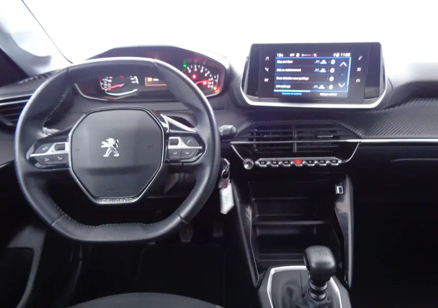 Intérieur de Peugeot 208 rouge Elixir, vue du poste de conduite avec volant compact et écran tactile central.