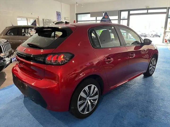 Vue 3/4 arrière droite d'une Peugeot 208 rouge Elixir Metal en intérieur, avec feux arrière LED distinctifs.