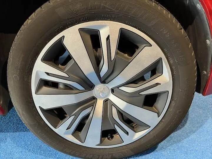 Gros plan sur la jante en alliage et pneu Michelin d'une Peugeot 208 rouge Elixir Metal, côté avant droit.