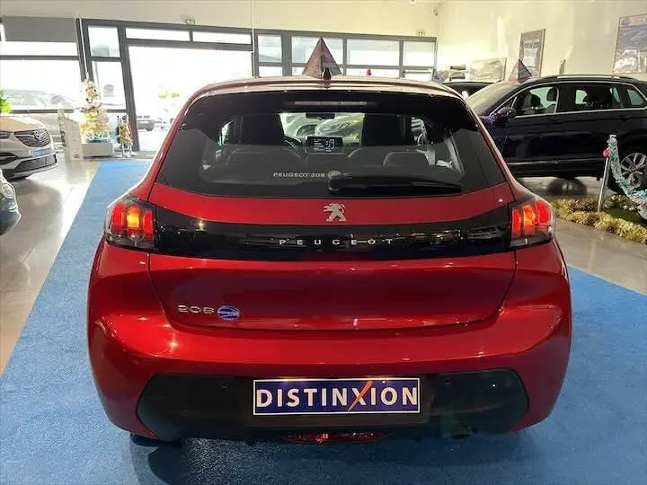 Vue arrière d'une Peugeot 208 rouge Elixir Metal exposée en showroom avec logo et plaque Distinxion visibles.