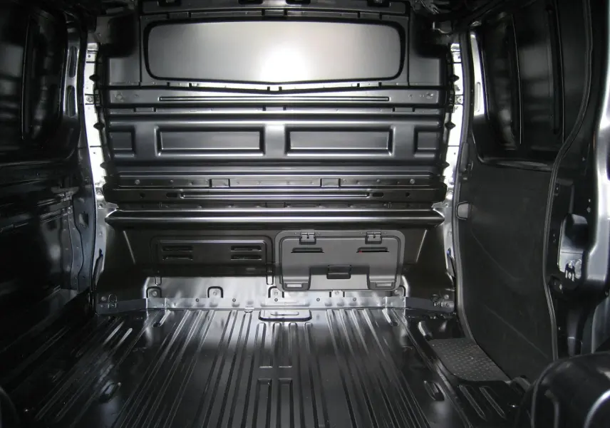 Vue intérieure arrière du fourgon Renault Trafic L1H1 Advance gris comète, montrant l'espace de chargement vide et métallique.