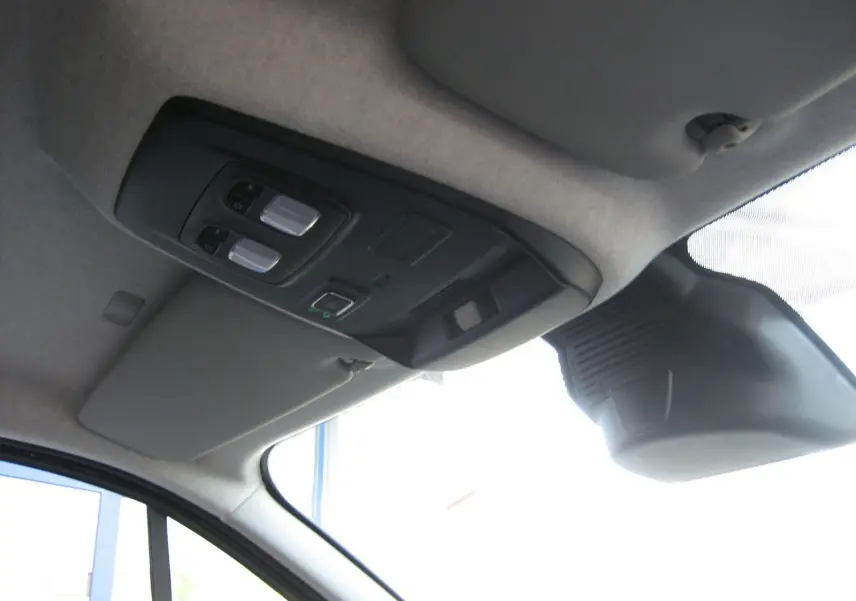 Vue intérieure du plafond avant du Renault Trafic Fourgon gris comète, avec commandes d'éclairage et pare-soleil côté conducteur.