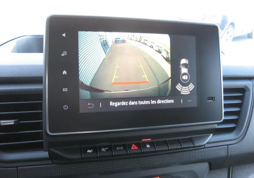 Écran central du Renault Trafic Fourgon gris comète montrant la caméra de recul avec lignes de guidage et alertes sonores.
