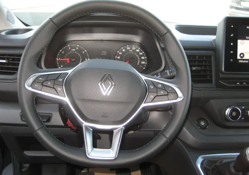 Vue rapprochée du volant noir du Renault Trafic Fourgon L1H1 Advance 2025 avec commandes intégrées et tableau de bord visible.