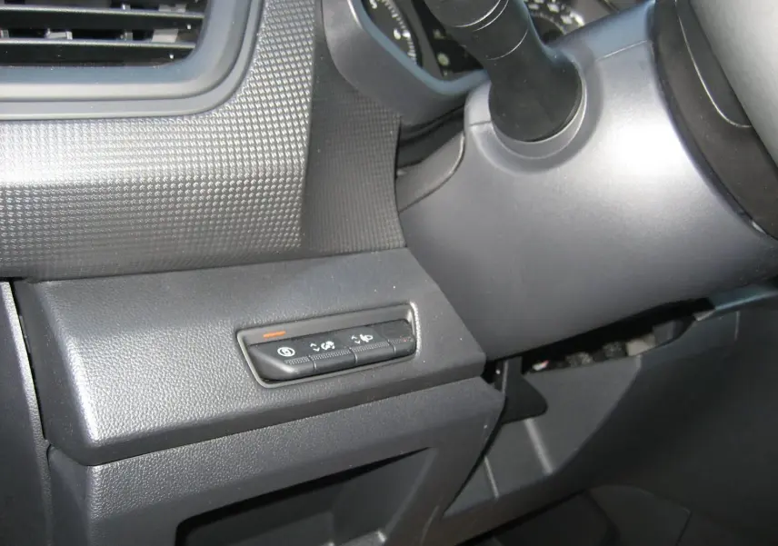 Vue rapprochée des commandes situées à gauche du volant dans l'habitacle du Renault Trafic Fourgon gris comète 2025.