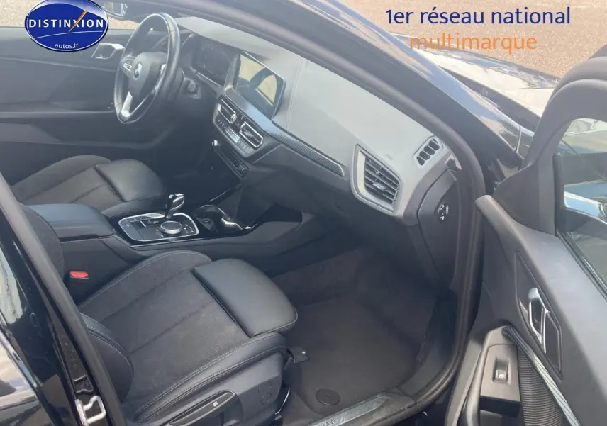 Vue intérieure côté conducteur de la BMW Série 1 noire, montrant sièges sport et tableau de bord moderne.