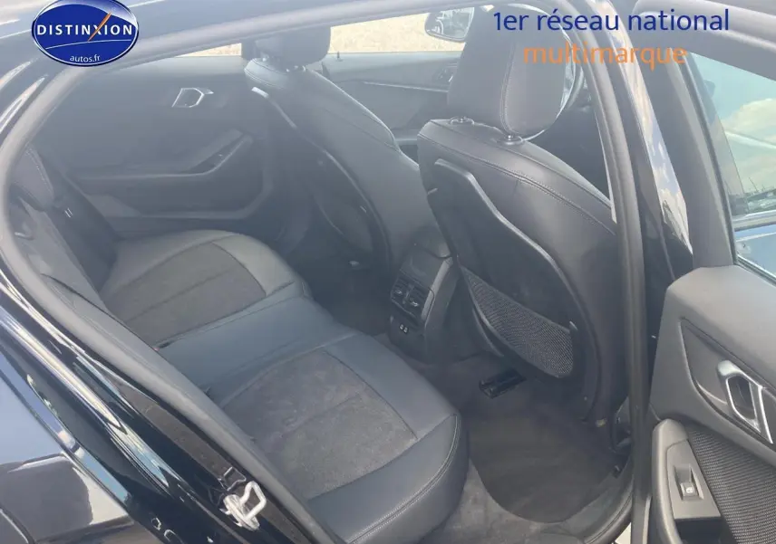 Vue intérieure arrière côté droit de la BMW Série 1 noire 118i 2023, sièges sport en tissu et similicuir anthracite.