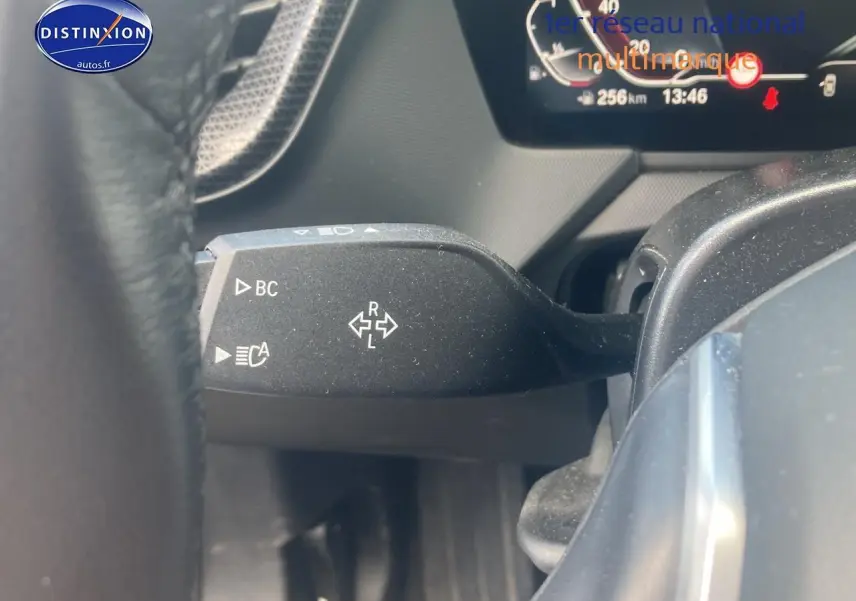 Gros plan sur la commande de clignotant à gauche du volant dans l’habitacle d’une BMW Série 1 noire 2023.