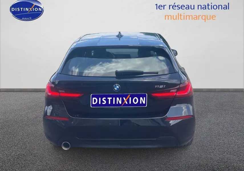 Vue arrière d'une BMW Série 1 118i noire de 2023 avec feux LED allumés et sortie d'échappement chromée côté gauche.