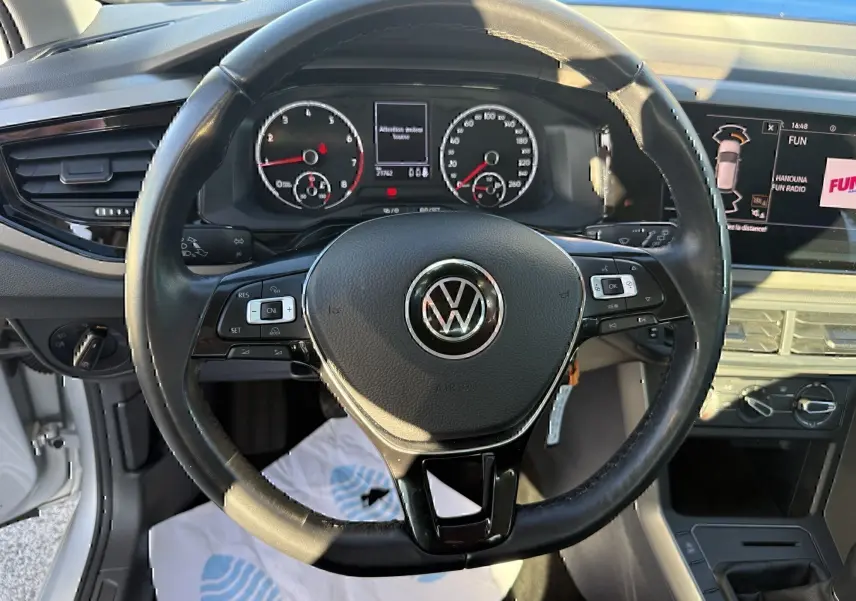 Vue intérieure centrée sur le volant noir de la Volkswagen Polo 1.0 TSI 95 Lounge Business 2021 avec tableau de bord et écran tactile.