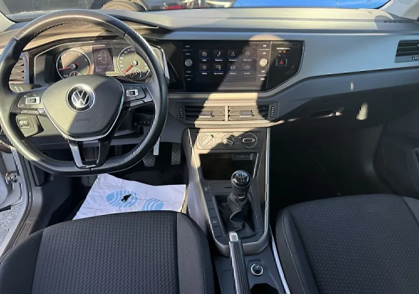 Vue intérieure avant de la Volkswagen Polo 1.0 TSI 95 Lounge Business 2021, volant multifonction et boîte manuelle visibles.