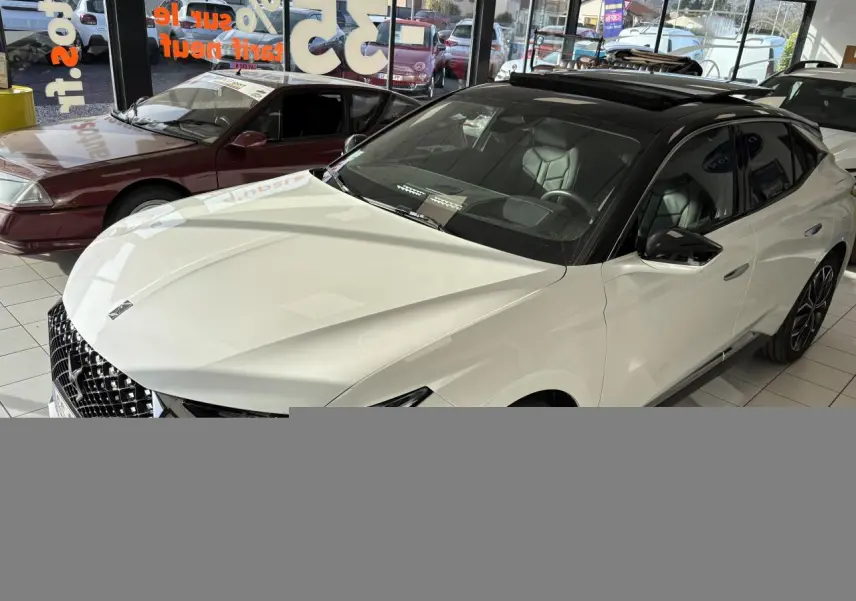 Vue 3/4 avant droite d'une DS4 E-Tense 2023 avec toit noir Perla Nera et carrosserie blanche nacrée en showroom.