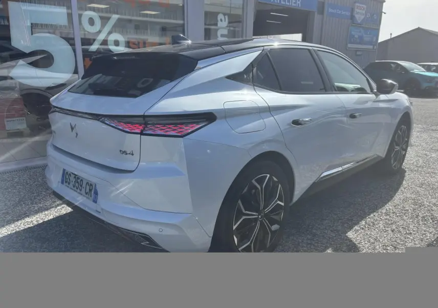 Vue 3/4 arrière droite d'une DS4 blanche avec feux arrière LED et jantes alliage noires devant un atelier Bosch.