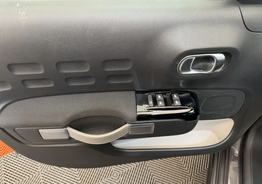 Vue rapprochée de la porte côté conducteur de la Citroën C3 gris foncé, avec commandes de vitres et poignée intégrée.