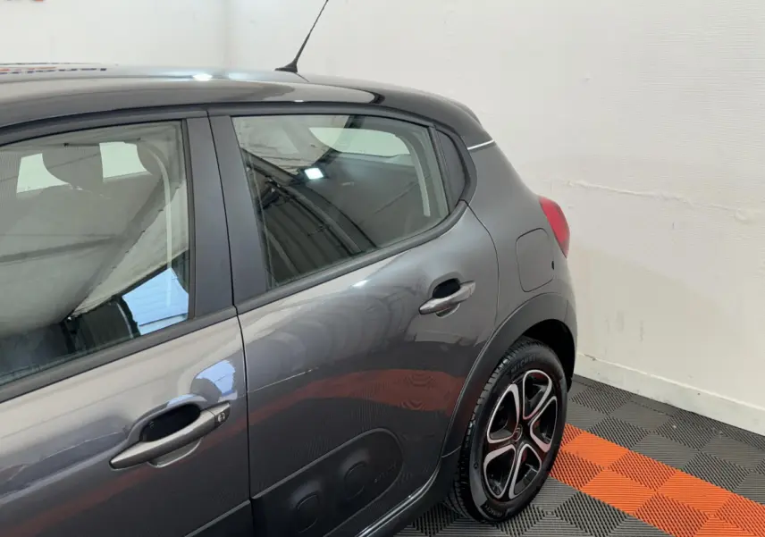 Vue côté arrière droit d'une Citroën C3 gris foncé avec jantes alliage et protections latérales noires.