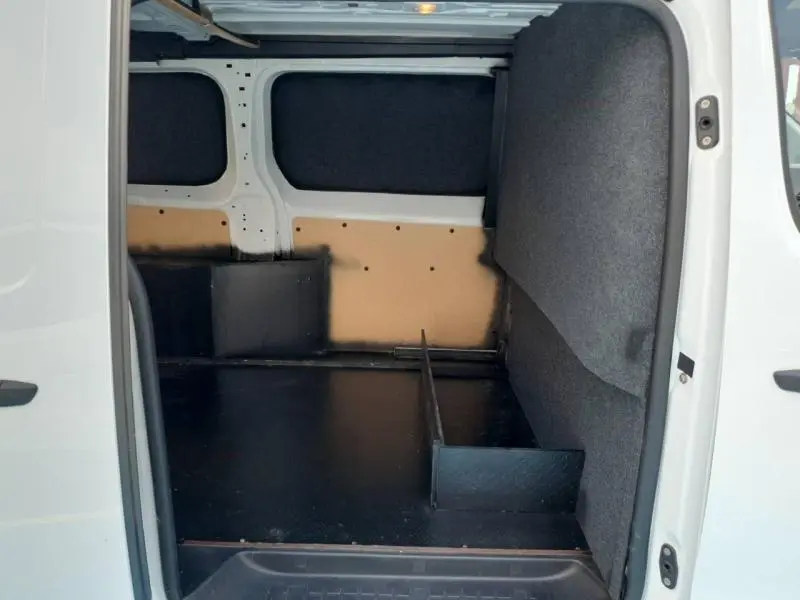 Vue intérieure côté droit du fourgon Peugeot Expert XL blanc, montrant l'espace de chargement avec cloison et revêtement noir.