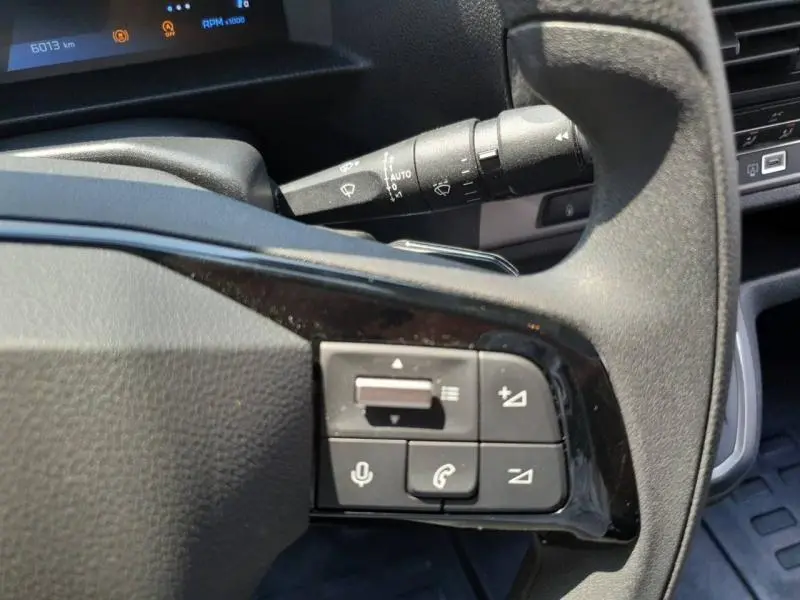 Gros plan sur les commandes audio et téléphone au volant du Peugeot Expert Fourgon blanc, tableau de bord en arrière-plan.