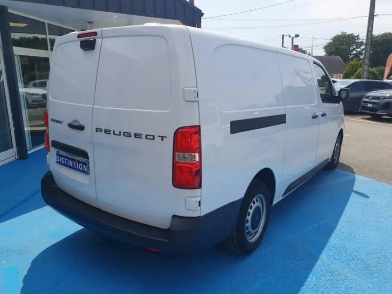 Vue 3/4 arrière droite d’un Peugeot Expert Fourgon blanc avec porte latérale coulissante et feux arrière rouges.