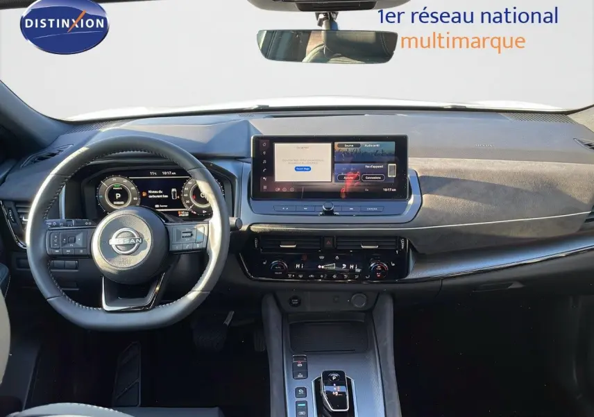 Vue intérieure du tableau de bord du Nissan Qashqai blanc nacré, avec écran tactile et volant multifonction.
