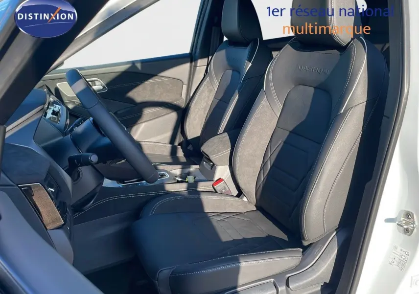 Intérieur du Nissan Qashqai blanc nacré, vue côté conducteur, sièges noirs en cuir avec surpiqûres blanches et logo Qashqai.