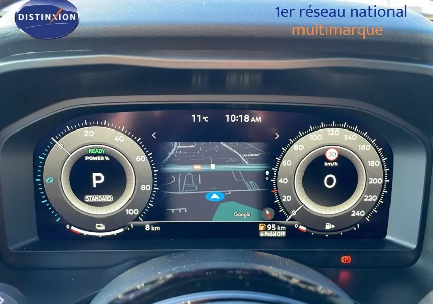 Tableau de bord numérique du Nissan Qashqai blanc nacré, affichant la navigation et les compteurs à 10h18.