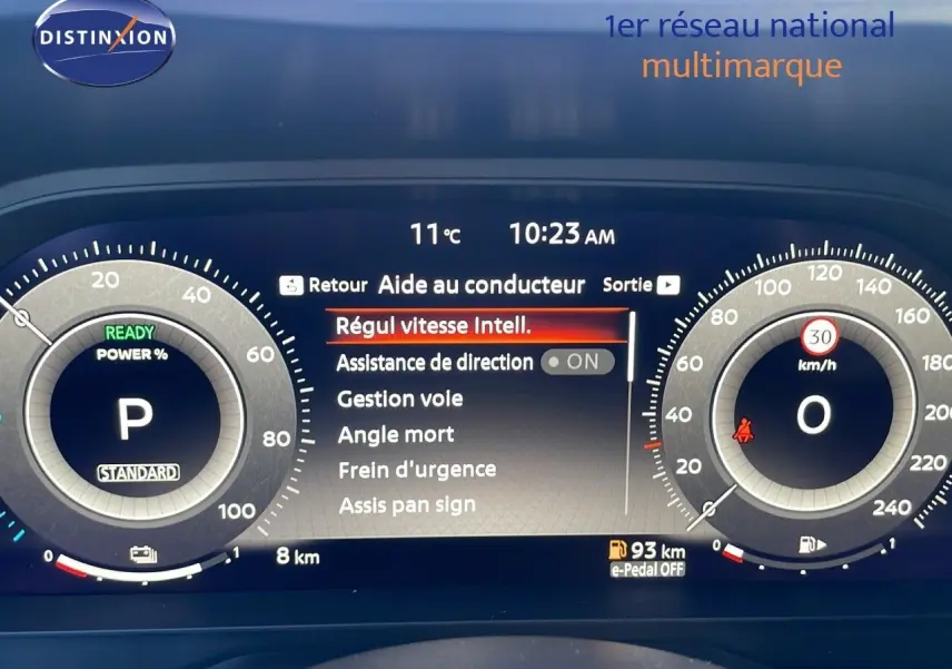 Tableau de bord numérique du Nissan Qashqai blanc nacré, affichant l'aide au conducteur et la vitesse à 0 km/h.