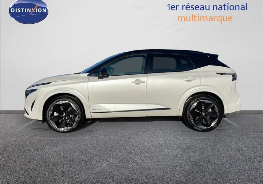 Nissan Qashqai blanc nacré avec toit noir en profil droit, soulignant ses jantes noires distinctives.