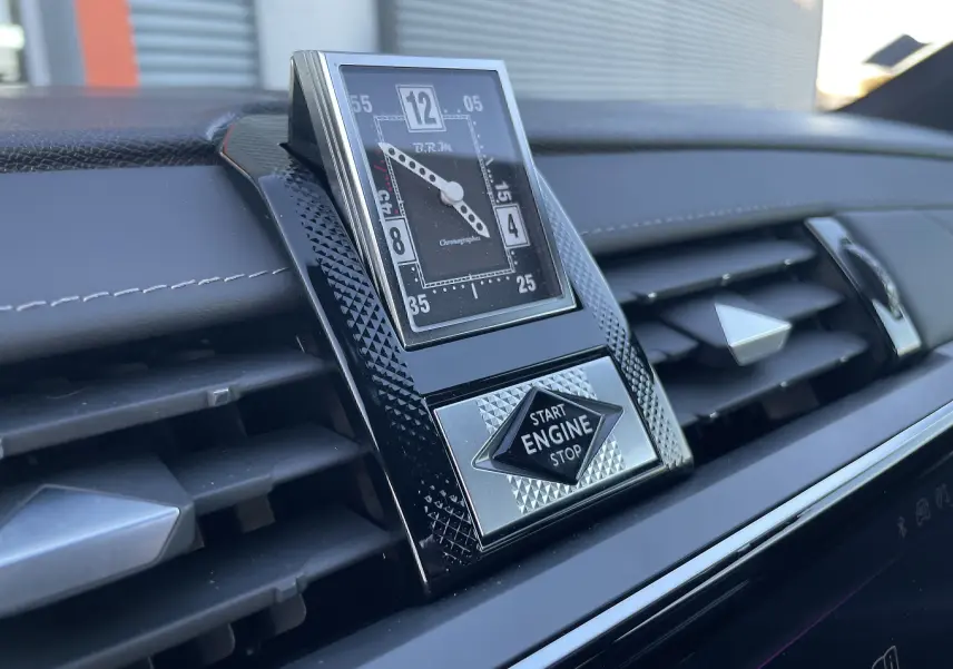 Gros plan sur l'horloge BRM et le bouton start/stop intégrés au tableau de bord noir du DS7 2024.