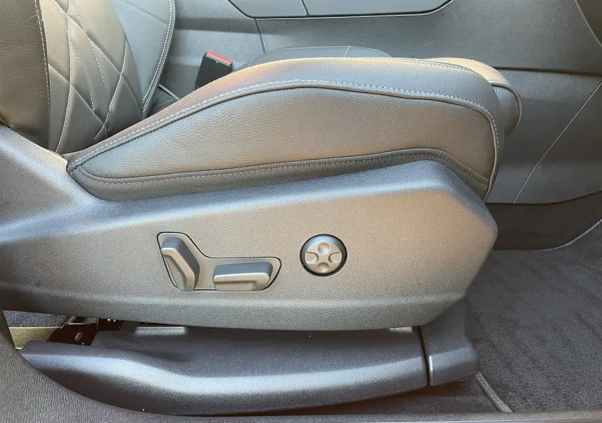 Gros plan sur les commandes de réglage électrique du siège avant droit en cuir noir du DS7 2024 Noir Perla Nera.