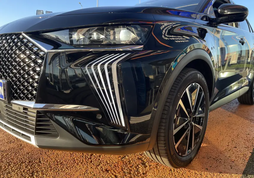 Gros plan sur l'avant droit du DS7 noir Perla Nera 2024, mettant en valeur ses feux LED distinctifs et sa calandre chromée.