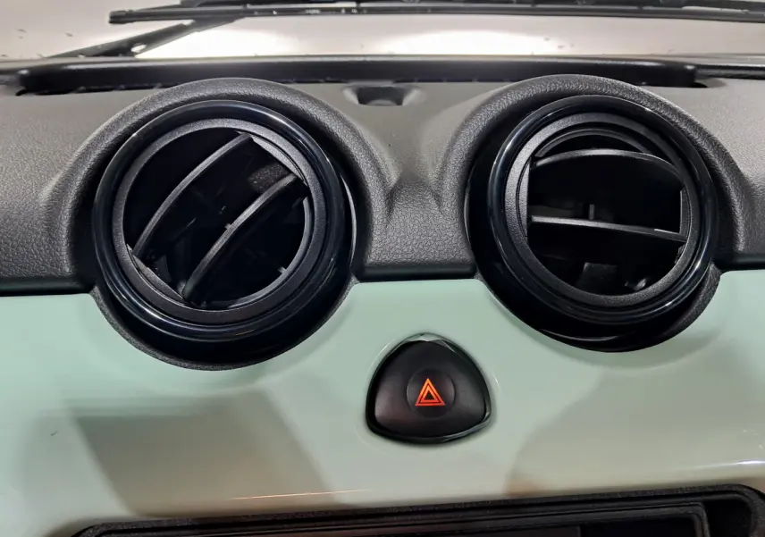 Gros plan sur les aérateurs noirs et le tableau de bord vert clair de l'AIXAM MINAUTO E chic 2025 électrique.