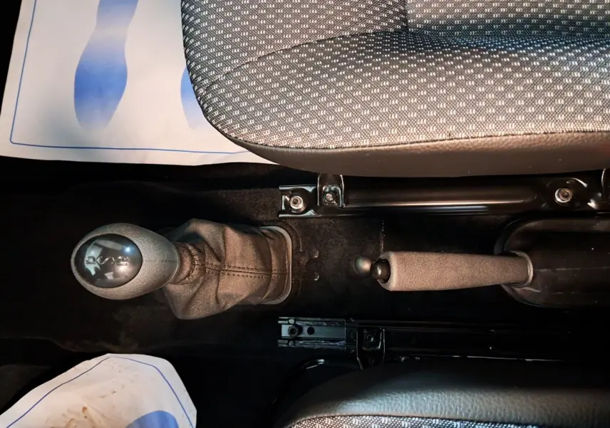 Gros plan intérieur montrant levier de boîte automatique et frein à main entre sièges tissu gris d'une Aixam Minauto E chic 2025.