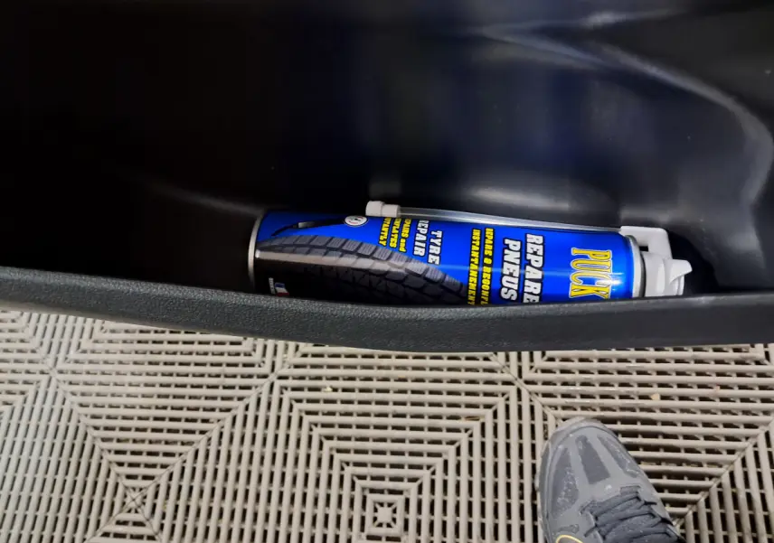 Vue intérieure du coffre d'une Aixam Minauto E chic 2025, avec bombe de réparation pneus visible et sol en plastique.