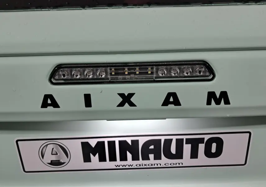 Gros plan sur la face avant verte de l'AIXAM MINAUTO E chic 2025 avec éclairage LED et logo visible.