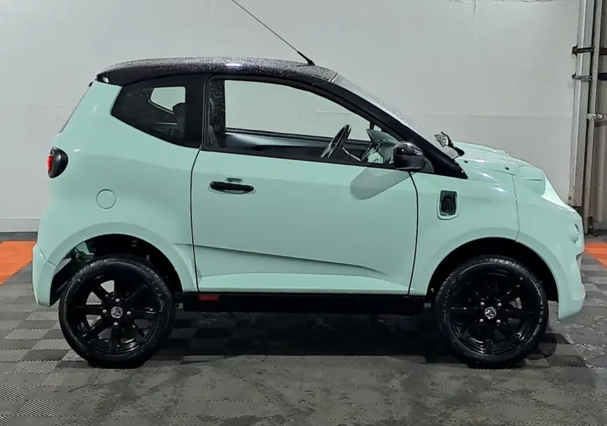 Profil côté gauche de l'AIXAM MINAUTO E chic 2025 en vert clair avec toit noir et jantes noires.