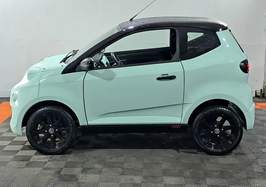 Profil côté gauche d'une AIXAM MINAUTO E chic 2025 électrique vert clair avec toit noir et jantes noires.