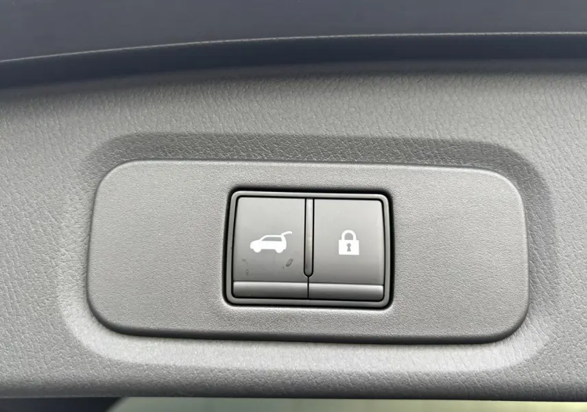 Gros plan sur les boutons d'ouverture électrique du hayon et de verrouillage, intérieur gris du Nissan Qashqai 2025.