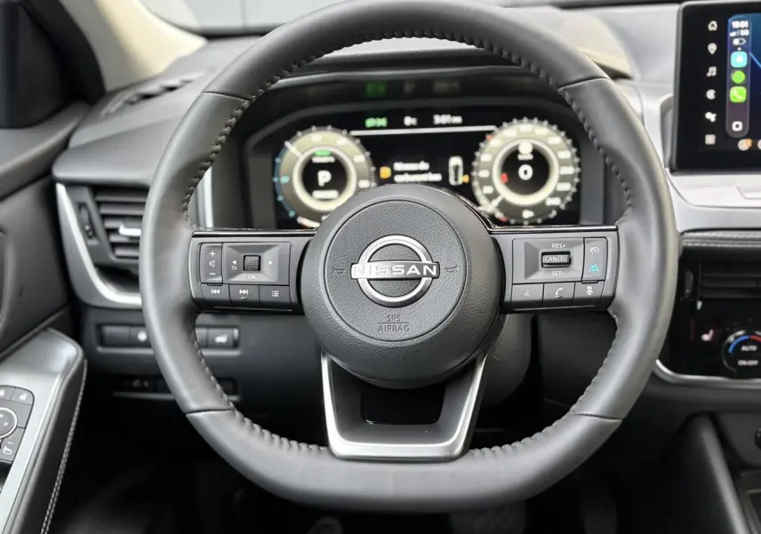 Vue rapprochée du volant cuir noir du Nissan Qashqai 2025 avec tableau de bord numérique et écran tactile visible.