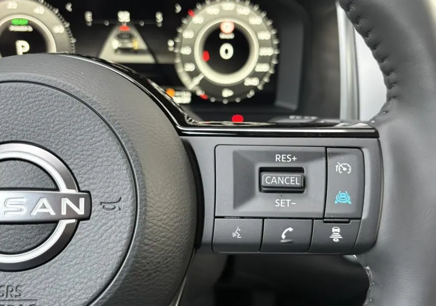 Gros plan sur le volant cuir noir du Nissan Qashqai III avec commandes de régulateur et aides à la conduite.