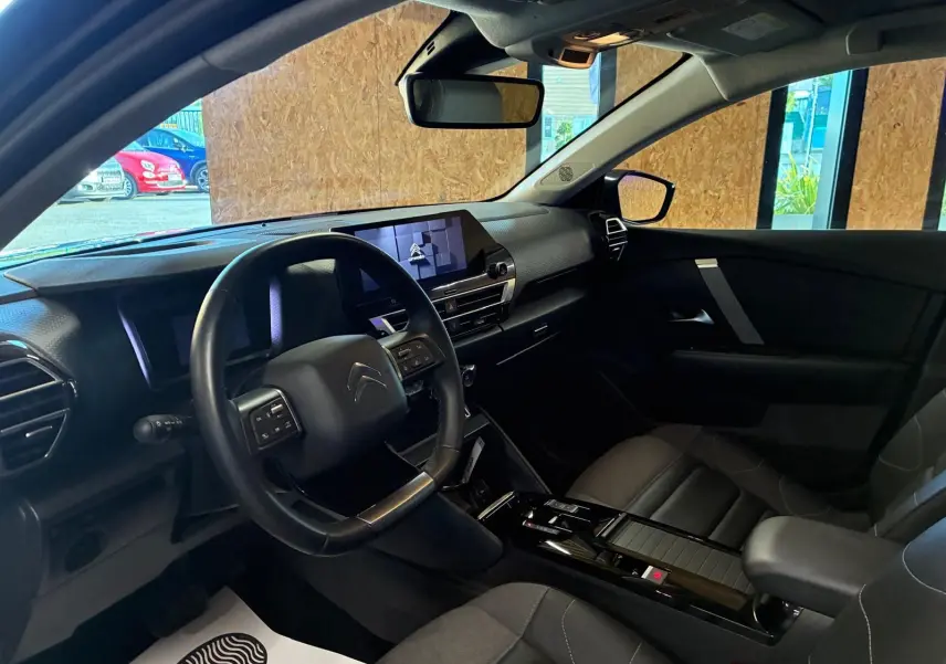 Vue intérieure côté conducteur du Citroën C4 X gris 2024, mettant en valeur le tableau de bord moderne et l'écran tactile central.