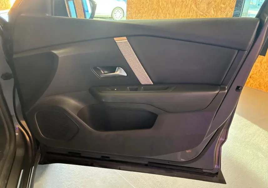 Vue intérieure de la porte côté gauche de la Citroën C4 X gris, avec poignée argentée et haut-parleur intégré.