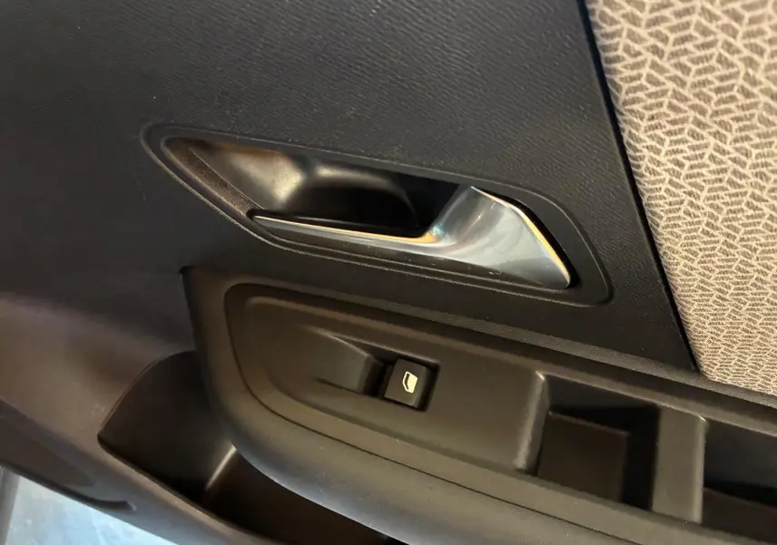 Poignée intérieure et commande de lève-vitre côté gauche d’une Citroën C4 X gris, avec habillage tissu gris clair.