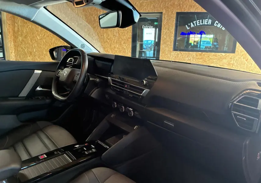 Vue intérieure côté conducteur du Citroën C4 X gris, mettant en valeur le tableau de bord moderne et le volant multifonction.